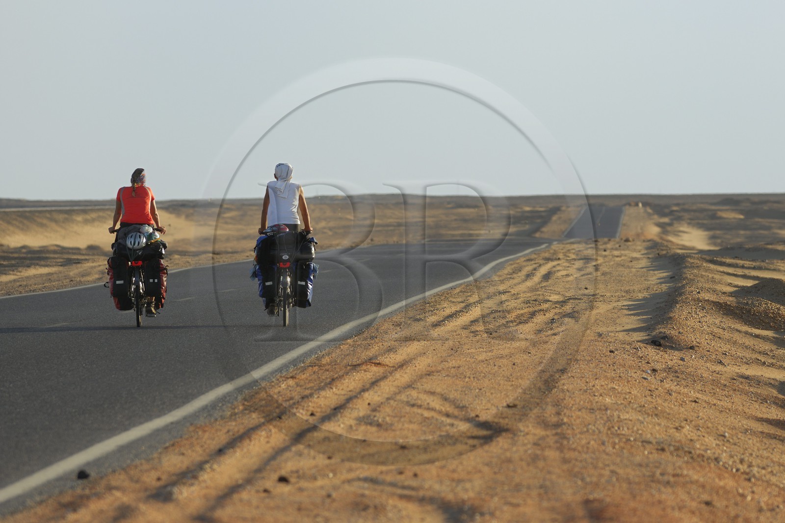 Egypt, Libyan desert, couple of cycling tourists on the road from Cairo to Bahareyya