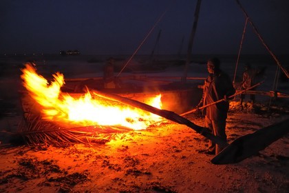 Tanzanie, archipel de Zanzibar, île de Unguja (Zanzibar), côte Sud-Est, Bwejuu, pêcheurs brûlant les algues sur un dhow (boutre traditionnel)