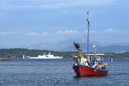 France, Var (83), Iles d'Hyères, parc national de Port Cros, Ile de Porquerolles, Bernard Samuel dit Sam le pêcheur sur son bateau, en arrière plan un navire de guerre en provenance de la rade de Toulon
