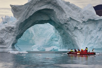 Greenland, North West coast, Baffin Sea, Inglefield Fjord towards Qaanaaq, iceberg forming an arch and an exploration PolarCirkel boat (zodiac) of the MS Fram cruse ship from Hurtigruten