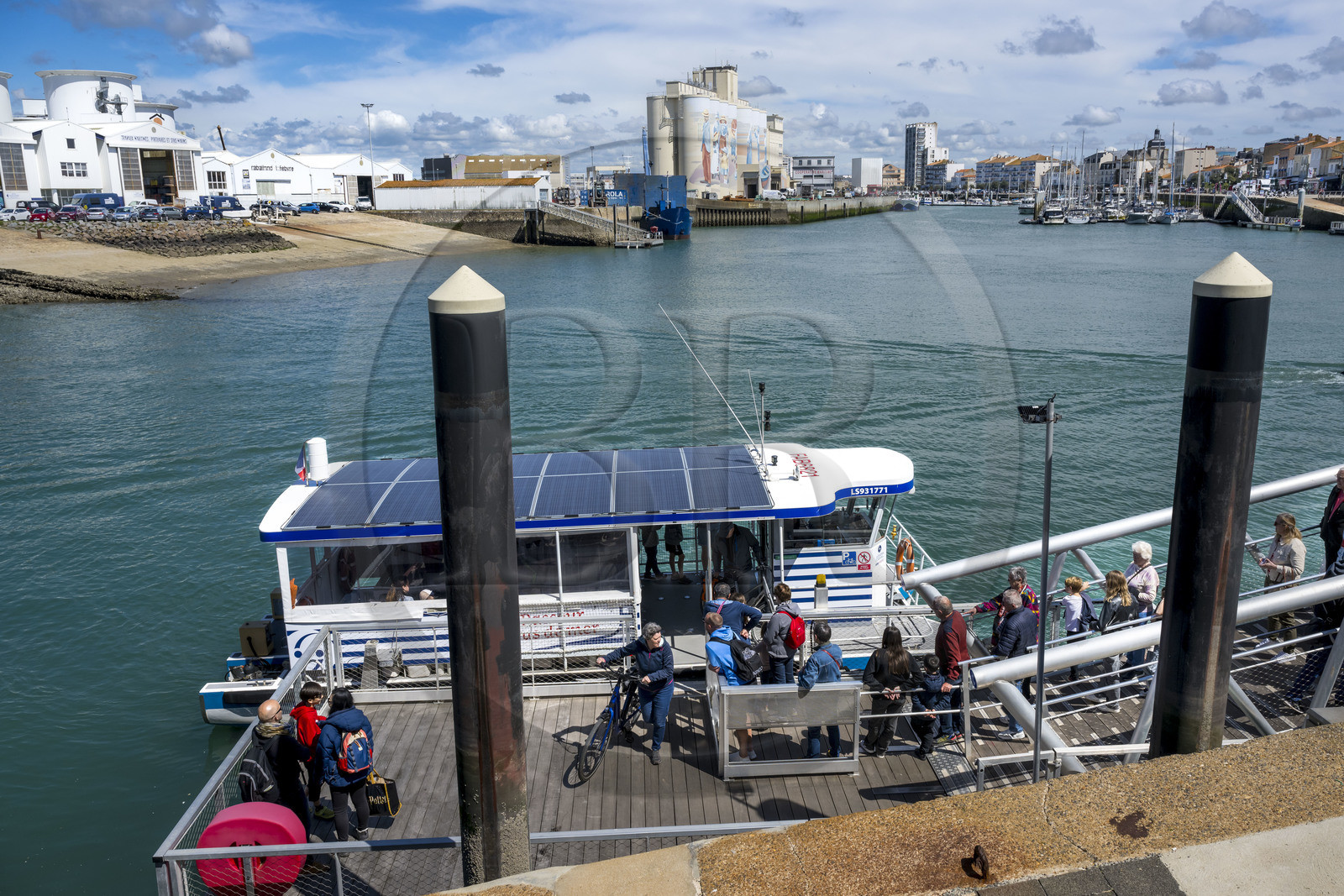 France, Vendee, Les Sables d'Olonne, cyclists using the ferry crossing the port, fresco retracing the history of the city painted on the silos of the Cavac cooperative by the Basque artist Taroe in the background