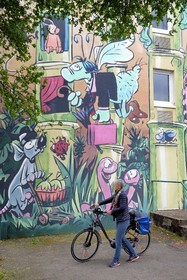 France, Charente (16), Angoulême, Rue Pierre Sémard , cycliste faisant la véloroute La Flow Vélo devant Le Jardin Extraordinaire, mur peint d'après un dessin original de Florence Cestac et réalisé par la Cité de la création en 2001